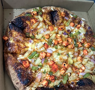 Well-done pizza with tandoori-spiced cubes, pineapple, green peppers and onion
