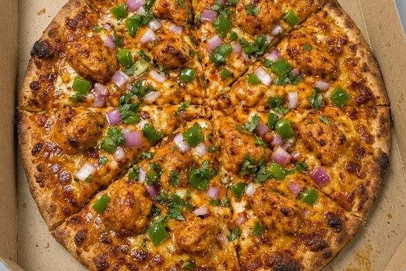 Sliced butter chicken pizza in an open pizza box