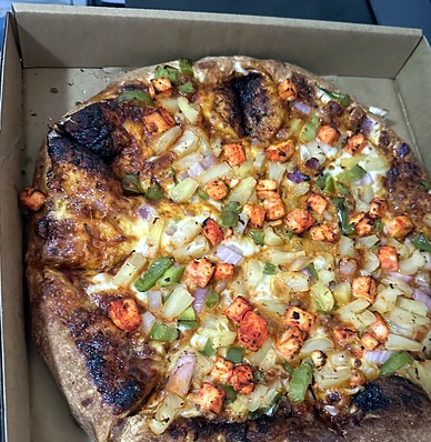 Well-done pizza with tandoori-spiced cubes, pineapple, green peppers and onion
