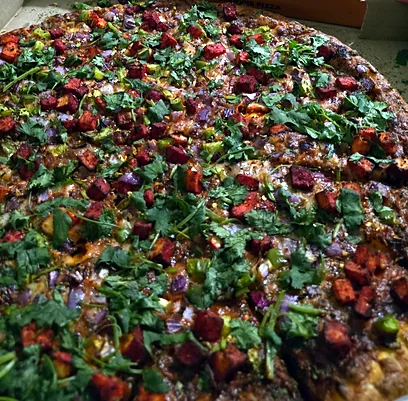 Pizza finished with fresh cilantro and spiced toppings